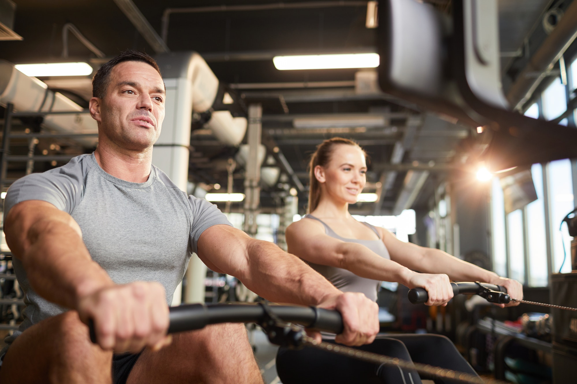 Fitness Couple Using Exercise Machine in Gym
