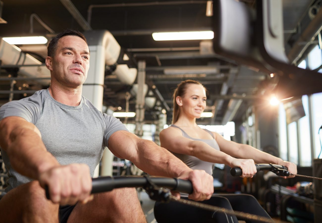 Fitness Couple Using Exercise Machine in Gym